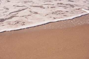 White foam on a sandy beach. Copy space.