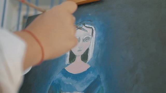 mano vista de cerca con pincel de artista dibujando cara retrato en caballete