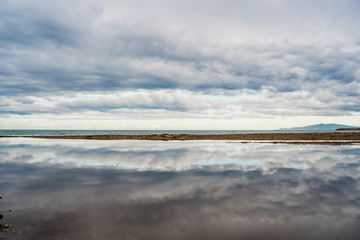 Reflection of the sky in a large puddle of rain and the Mediterranean sea in the background. Aguilas, Murcia, 