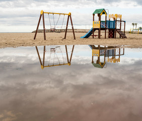 Reflection of children's attractions on the beach after the rain.
