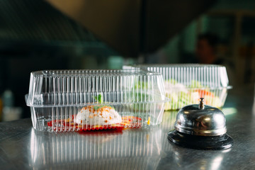 food delivery. distribution table in a restaurant with a metal bell. food in plastic containers....