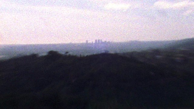 Shaky old looking archival footage of Los Angeles skyline and hills in the distance
