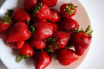 Close up. Fresh ripe delicious strawberries in a white bowl isolated on white background. Beautiful Italian red strawberry. European eco food without pesticides and additives in Milan, Lombardy, Italy