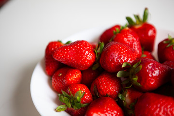 Close up. Fresh ripe delicious strawberries in a white bowl isolated on white background. Beautiful Italian red strawberry. European eco food without pesticides and additives in Milan, Lombardy, Italy