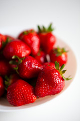 Close up. Fresh ripe delicious strawberries in a white bowl isolated on white background. Beautiful Italian red strawberry. European eco food without pesticides and additives in Milan, Lombardy, Italy