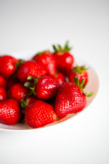Close up. Fresh ripe delicious strawberries in a white bowl isolated on white background. Beautiful Italian red strawberry. European eco food without pesticides and additives in Milan, Lombardy, Italy