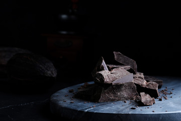 Pieces of tasty dark chocolate on grey marble board, closeup