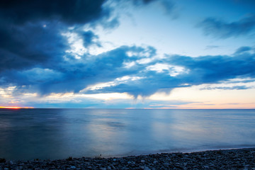 Obraz premium Rain clouds over ocean during sunset, long exposure