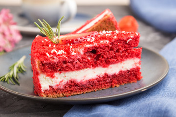 Homemade red velvet cake with milk cream and strawberry  with cup of coffee on a black concrete background. side view, selective focus.