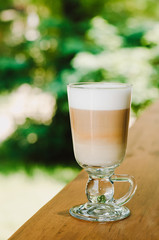 Hot latte coffee in glasse cup on a wooden table. Morning homemade coffee. Relaxing time concept. Copy space. Selective focus.
