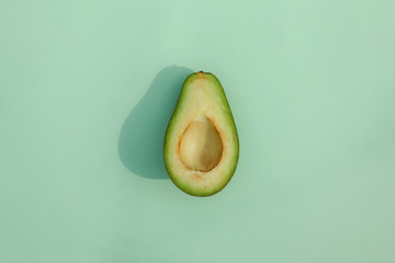avocado cut on a colored background top view with a hard shadow