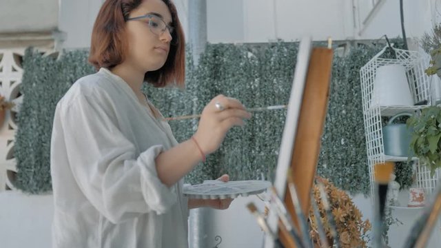 vista desde abajo de joven pintora con pincel y caballete de artista en patio