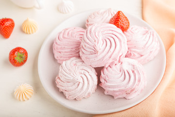 Pink strawberry homemade zephyr or marshmallow with cup of coffee on white wooden background. side view, selective focus.