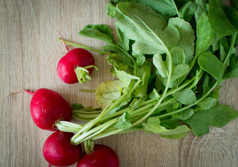Spring healthy meal with vegetables. Red radishes on wooden table, rustic effect.