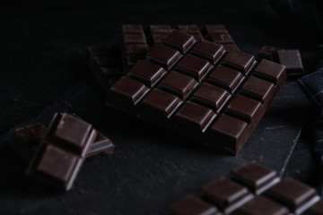 Tasty dark chocolate bars on black table
