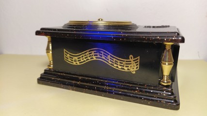 Old black music box. The notes are painted on the front side of the casket with gold paint. Treble...