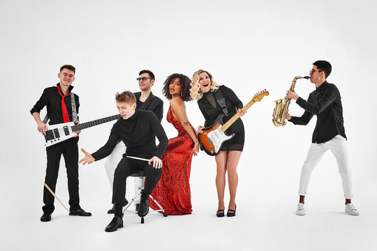 photo of multi ethnic music band in studio.Musicians and woman soloist posing over white background