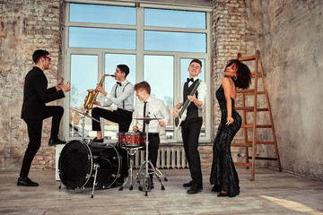 Repetition of multi ethnic jazz band in loft. Bass guitar player, electric guitar player,...