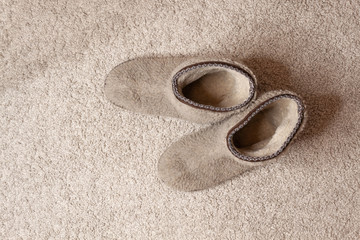 Fototapeta na wymiar Carpet texture. Soft cozy slippers at beige carpet floor 