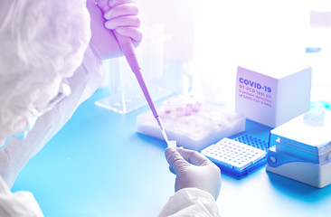 SARS-COV-2 pcr diagnostics kit. Epidemiologist in protective suit, mask and glasses works with...