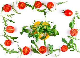 Halved tomatoes with rucola leaves and slice of yellow sweet pepper isolated on a white background. Top view.