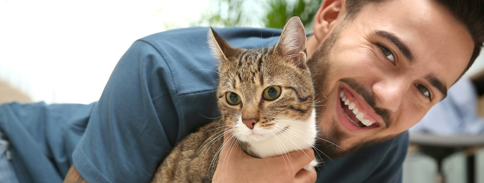 Happy young man with cat at home. Banner design