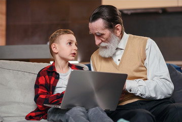 Grandson is teaching his grandfather to use laptop computer.