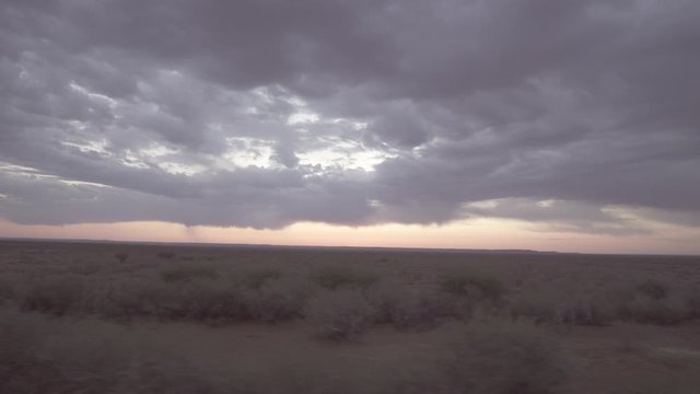 Panning shot of cloudy sky over landscape during sunset seen through moving train window - Swakopmund, Namibia