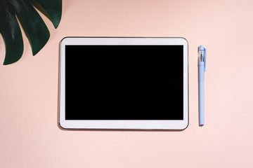 A tabletand pen and partly a leaf of monstera.