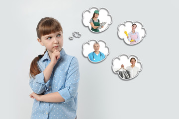 Fototapeta premium Thoughtful little girl choosing future profession on light background