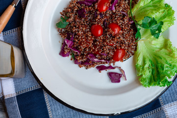 Red quinoa salad with tomato on a rustic table. Superfood and healthy eating concept.
