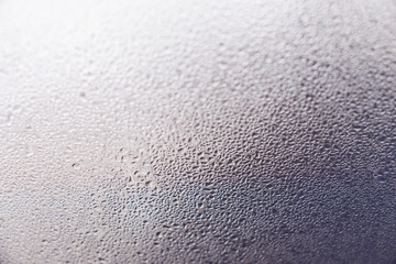 Closeup photo of a foggy window glass in drops of water.