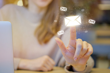 The girl in the cafe abstractly clicks a finger on the icon with email.