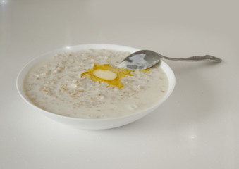 oatmeal with a slice of butter on a white table in the morning