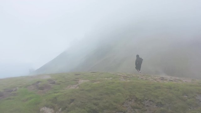 Drone view of man wayfarer in robes dancing in mountains