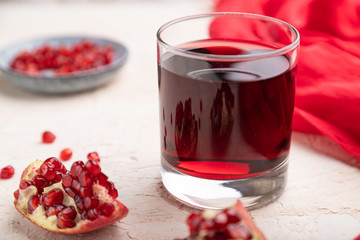 Glass of pomegranate juice on a white concrete background. Side view, selective focus