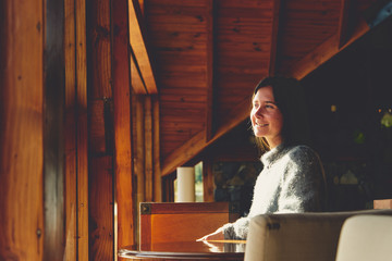 Bella chica relajándose y mirando frente a una ventana en una cabaña de madera.