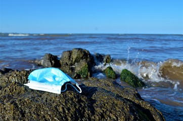 disposable face mask thrown on the beach
