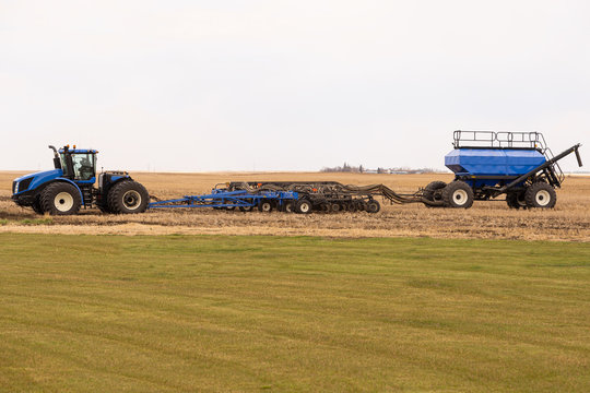 Tractor In The Field Ready To Begin Spring Planting And Fertilizing Crops In Canada