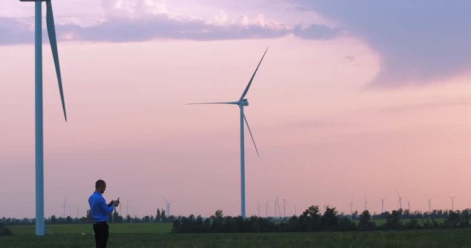 An engineer tries to tune a wind generator in the evening. The stopped wind generators against the backdrop of a beautiful twilight sky.