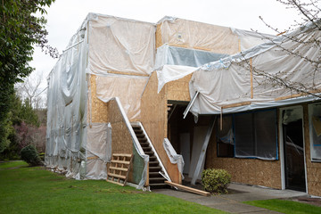 Wood framed building under construction covered in plastic sheeting during a work stoppage