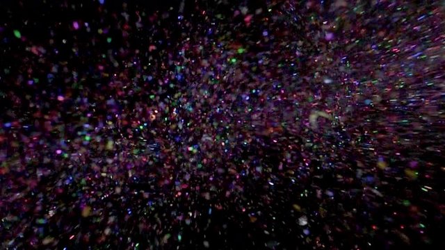 Multi-colored glitter bomb exploding and glitter falling from the sky from black background