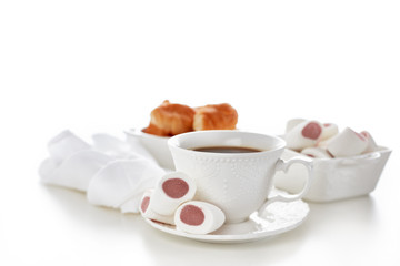 Obraz na płótnie Canvas Still life with cup of coffee and bowls with marshmallows and croissants on white background. Sweet meal. Dessert