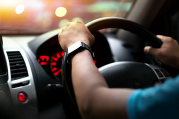 Selective focus hand of man. Hold the steering wheel of the car. Outside of the car glass is a warm...