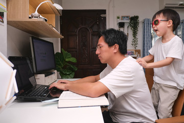 Asian boy want to play with his busy working at home dad. Businessman working from home, Child at...