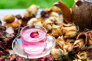 Organic tea rose made from tea  rose petals in a glass bowl on the wooden rustic background around with dry rose petals
