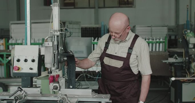Serious engineer examining and checking serviceability of machine on a factory