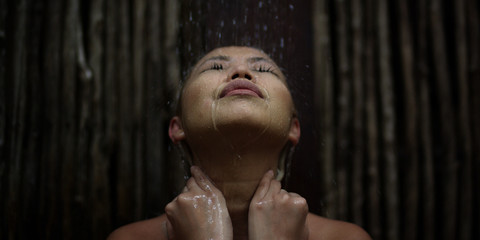 Fototapeta na wymiar Woman holds her neck massaging herself letting water wash over her after a long day feeling refreshed and content while at a spa