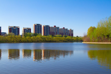 Fototapeta na wymiar Modern apartment buildings by a lake with shadows in the water mirror reflection Spring