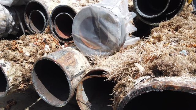 Old multi string casing conductors are cut with welding torch and laid down together on the deck of the drilling rig.
